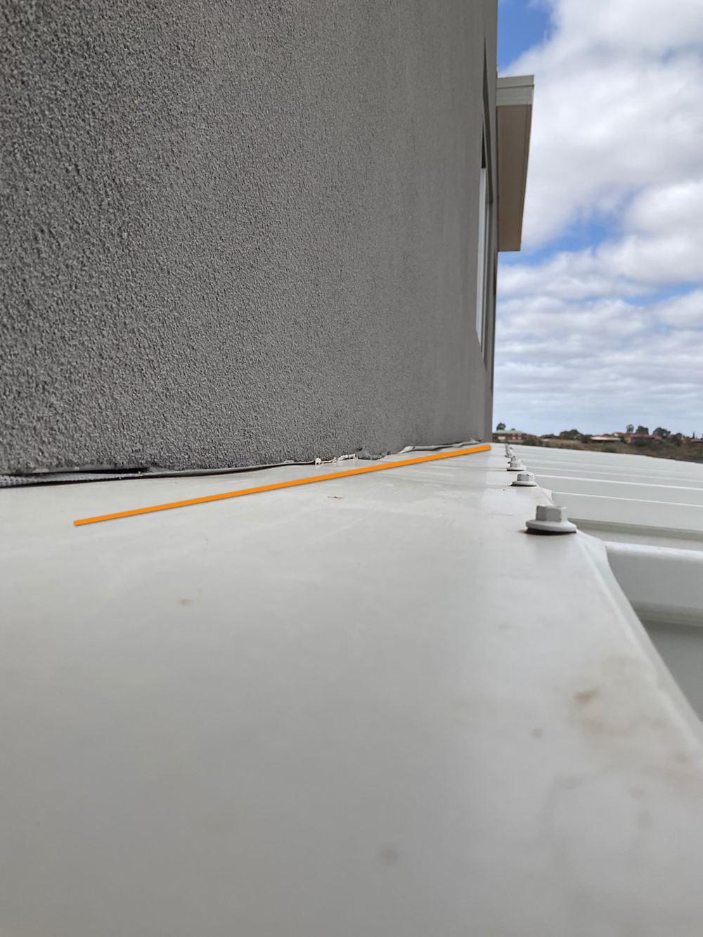 Gap between the lightweight panel wall and roof sheet that traps water, found during a pre-handover inspection in Bacchus Marsh